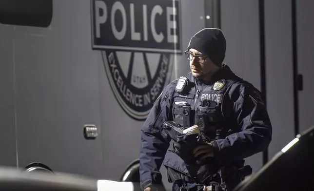 An officer walks past a command trailer as police investigate a crime scene where they say multiple family members were found dead inside a home in West Valley City, Utah, Tuesday Dec. 17, 2024. (Scott G. Winterton/The Deseret News via AP)