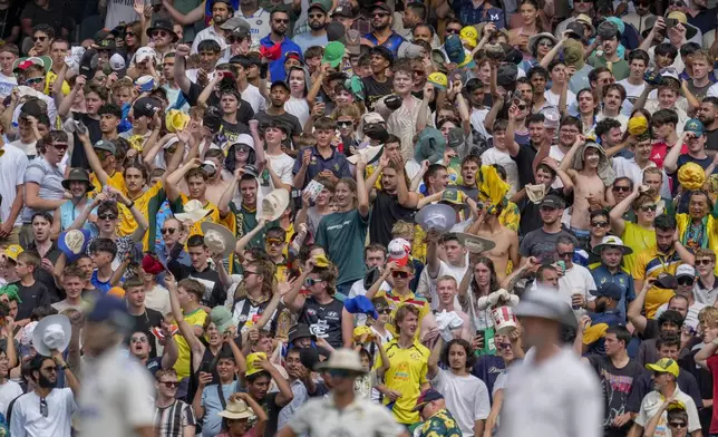 Spectators pay tribute to Shane Warne by wave their hats during play on the last day of the fourth cricket test between Australia and India at the Melbourne Cricket Ground, Melbourne, Australia, Monday, Dec. 30, 2024. (AP Photo/Asanka Brendon Ratnayake)