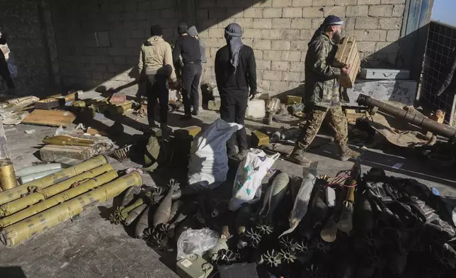 Syrian opposition fighters seize ammunition abandoned by the army in the town of Khan Assubul, Syria, southwest of Aleppo, Sunday, Dec. 1, 2024. Insurgents launched a two-pronged attack on Aleppo and the countryside around Idlib. (AP Photo/Ghaith Alsayed)