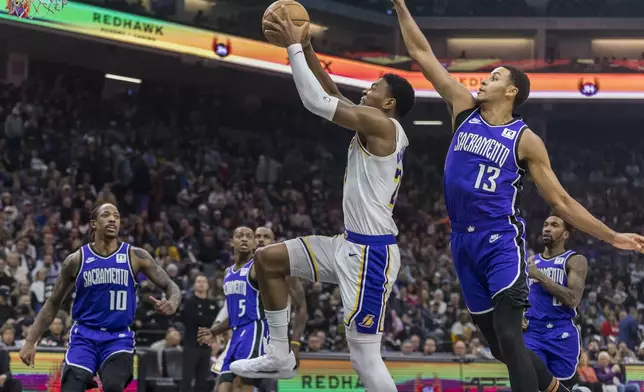 Los Angeles Lakers forward Rui Hachimura dunks with Sacramento Kings forward Keegan Murray (13) on defense during the first half of an NBA basketball game, Saturday, Dec. 21, 2024, in Sacramento, Calif. (AP Photo/Sara Nevis)