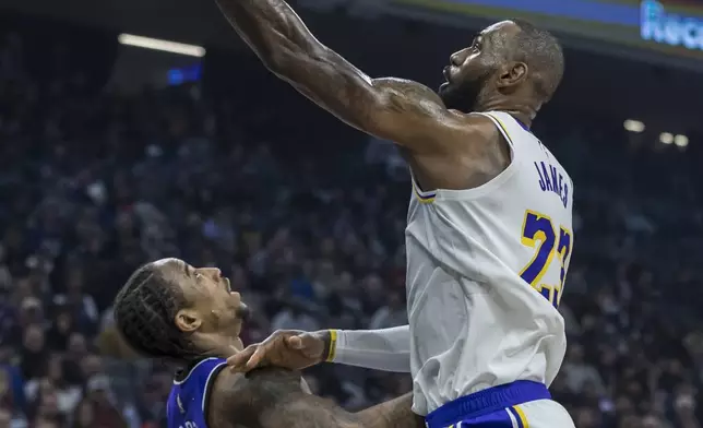 Los Angeles Lakers forward LeBron James draws the foul on Sacramento Kings forward DeMar DeRozan during the first half of an NBA basketball game, Saturday, Dec. 21, 2024, in Sacramento, Calif. (AP Photo/Sara Nevis)