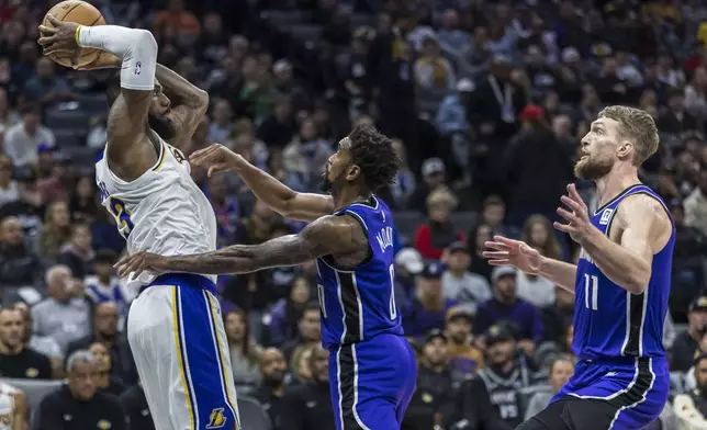 Los Angeles Lakers forward LeBron James (23) looks to pass the ball with Sacramento Kings guard Malik Monk (0) defending during the first half of an NBA basketball game, Saturday, Dec. 21, 2024, in Sacramento, Calif. (AP Photo/Sara Nevis)