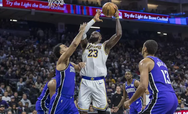 Los Angeles Lakers forward LeBron James (23) makes a layup over Sacramento Kings forward Trey Lyles (41) during the first half of an NBA basketball game Saturday, Dec. 21, 2024, in Sacramento, Calif. (AP Photo/Sara Nevis)