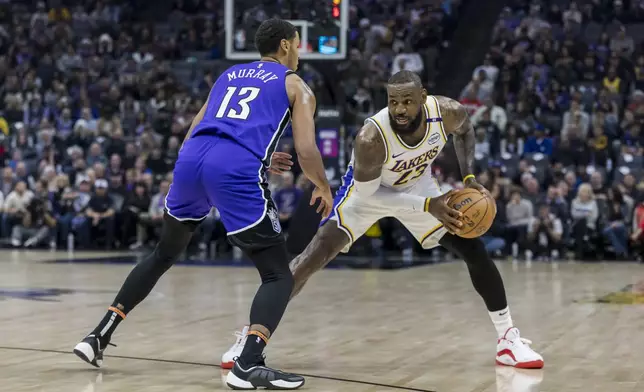 Los Angeles Lakers forward LeBron James backs up Sacramento Kings forward Keegan Murray (13) at the 3-point line during the first half of an NBA basketball game Saturday, Dec. 21, 2024, in Sacramento, Calif. (AP Photo/Sara Nevis)