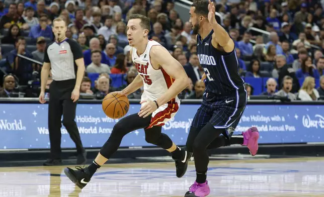 Miami Heat forward Duncan Robinson, left, drives down court against Orlando Magic guard Trevelin Queen, right, during the first half of an NBA basketball game, Thursday, Dec. 26, 2024, in Orlando, Fla. (AP Photo/Kevin Kolczynski)