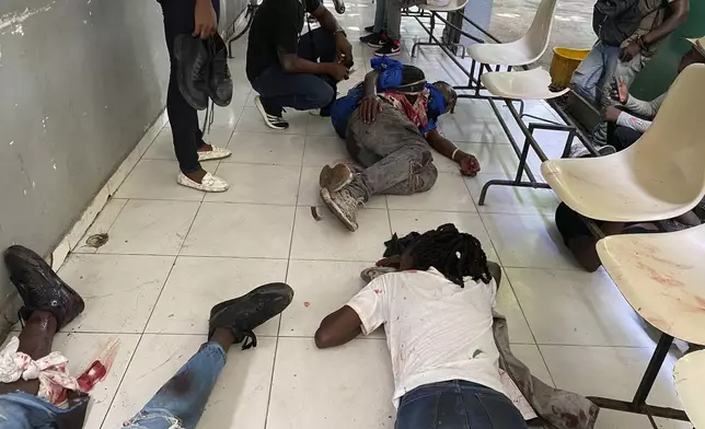 Journalists lie wounded after being shot by armed gangs at the general hospital in Port-au-Prince, Haiti, Tuesday, Dec. 24, 2024. (AP Photo/Dieugo Andre)