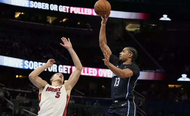 Orlando Magic guard Jett Howard (13) shoots over Miami Heat forward Nikola Jovic (5) during the second half of an NBA basketball game, Saturday, Dec. 21, 2024, in Orlando, Fla. (AP Photo/John Raoux)