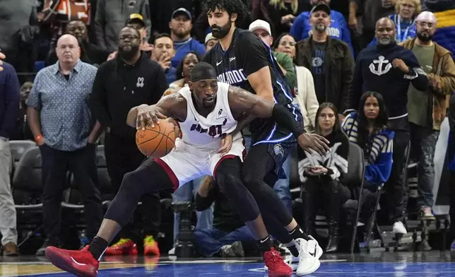 Miami Heat center Bam Adebayo, left, is pressured by Orlando Magic center Goga Bitadze as he tries to get to the basket during the second half of an NBA basketball game, Saturday, Dec. 21, 2024, in Orlando, Fla. (AP Photo/John Raoux)