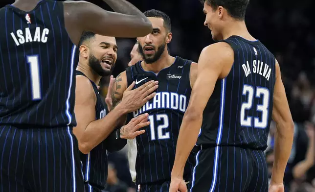 Orlando Magic players from left, Jonathan Isaac (1), Cory Joseph, Trevelin Queen (12) and Tristan da Silva (23) celebrate a win during the final moments an NBA basketball game against the Miami Heat, Saturday, Dec. 21, 2024, in Orlando, Fla. (AP Photo/John Raoux)