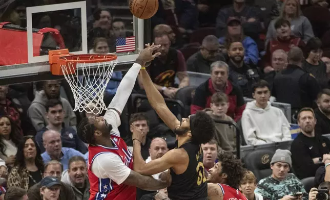 Philadelphia 76ers' Andre Drummond, left blocks a shot by Cleveland Cavaliers' Jarrett Allen, right, during the first half of an NBA basketball game in Cleveland, Saturday Dec. 21, 2024. (AP Photo/Phil Long)