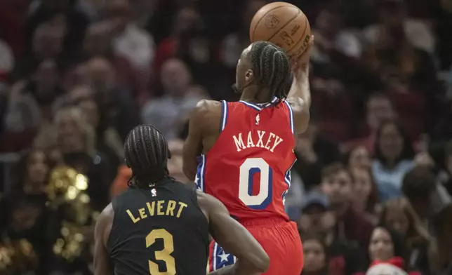 Philadelphia 76ers' Tyrese Maxey (0) shoots as Cleveland Cavaliers' Caris LeVert (3) looks on during the first half of an NBA basketball game in Cleveland, Saturday Dec. 21, 2024. (AP Photo/Phil Long)