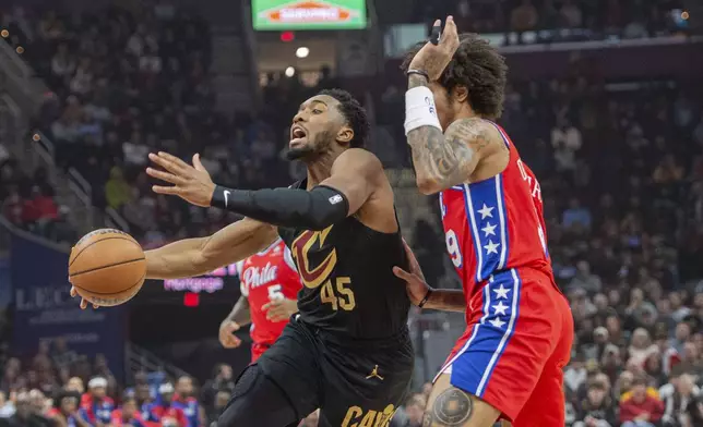 Cleveland Cavaliers' Donovan Mitchell (45) drives to the basket as Philadelphia 76ers' Kelly Oubre Jr., right, defends during the first half of an NBA basketball game in Cleveland, Saturday Dec. 21, 2024. (AP Photo/Phil Long)