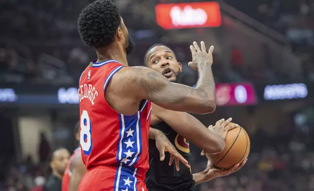 Philadelphia 76ers' Paul George (8) defends as Cleveland Cavaliers' Evan Mobley, rear looks to pass during the first half of an NBA basketball game in Cleveland, Saturday Dec. 21, 2024. (AP Photo/Phil Long)