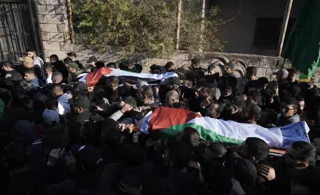 Mourners carry the bodies wrapped with the Palestinian flag, of Akram Abu Arrah and Mohammad Ghannam, both killed in an airstrike Israel said targeted a militant cell, during their funeral in the West Bank village of Al-Aqaba, Tuesday Dec. 3, 2024. (AP Photo/Majdi Muhammad)