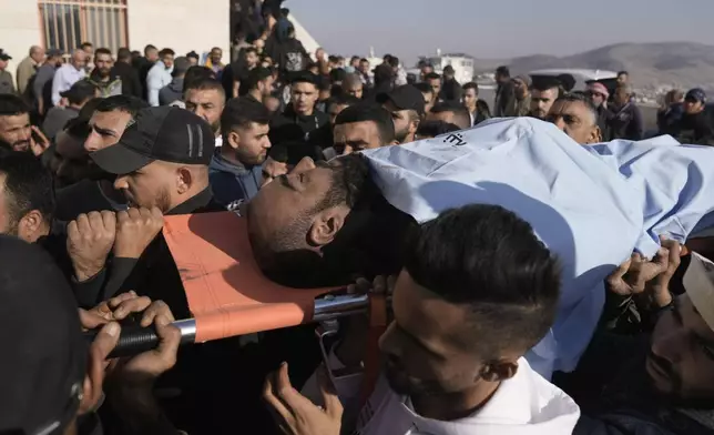 Mourners carry the bodies of two Palestinians Akram Abu Arrah, seen, and Mohammad Ghannam, both killed in an airstrike Israel said targeted a militant cell, during their funeral in the West Bank village of Al-Aqaba, Tuesday Dec. 3, 2024. (AP Photo/Majdi Muhammad)