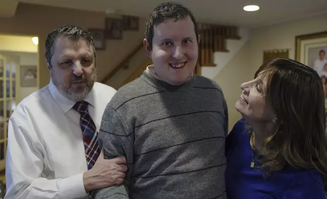 Dov Marcus smiles flanked by his parents, Robert Marcus and Debbie Marcus, in Teaneck, N.J., on Friday, Dec. 20, 2024. (AP Photo/Luis Andres Henao)