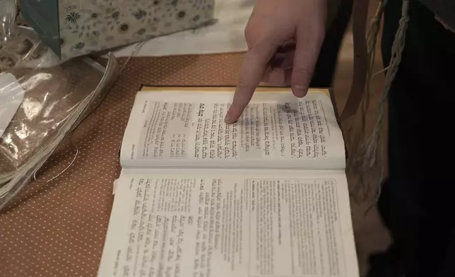 Dov Marcus points to prayers as he reads from the Jewish prayer book in Teaneck, N.J., on Friday, Dec. 20, 2024. (AP Photo/Luis Andres Henao)