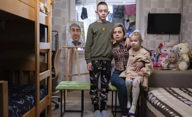 Natalia Sheleshei, 39, with her children Yehor, 12, and Anastasia, 5, wait for the return of Serhii at their apartment in Kyiv, Ukraine on Feb. 12, 2024. (AP Photo/Evgeniy Maloletka)