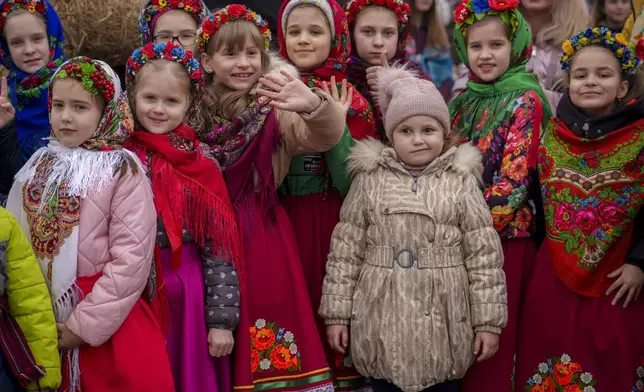 Children wearing traditional outfits wait before performing songs during a show of traditions for Masnytsia, a holiday that originates in pagan times, celebrating the end of winter, in Kyiv, Ukraine, Saturday, March 16, 2024. (AP Photo/Vadim Ghirda)