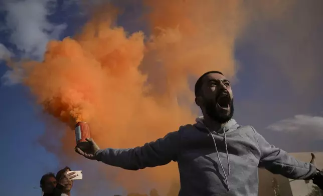 A man waves a flare during a celebratory demonstration following the first Friday prayers since Bashar Assad's ouster, in Damascus' central square, Syria, Friday, Dec. 13, 2024. (AP Photo/Leo Correa)