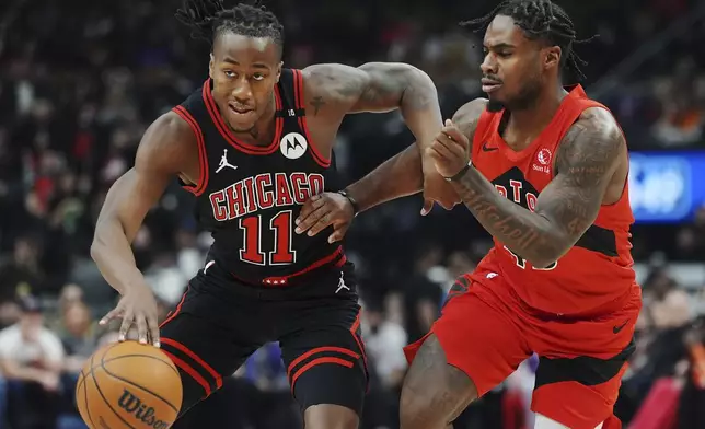 Chicago Bulls' Ayo Dosunmu (11) protects the ball from Toronto Raptors' Davion Mitchell, right, during first-half NBA basketball game action in Toronto, Monday, Dec. 16, 2024. (Frank Gunn/The Canadian Press via AP)