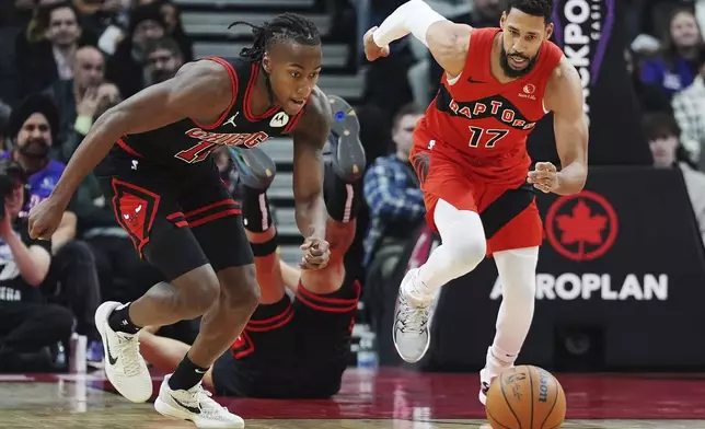 Chicago Bulls' Ayo Dosunmu, left, and Toronto Raptors' Garrett Temple (17) race for the ball during first-half NBA basketball game action in Toronto, Monday, Dec. 16, 2024. (Frank Gunn/The Canadian Press via AP)