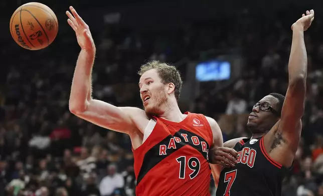 Toronto Raptors' Jakob Poeltl (19) and Chicago Bulls' Jalen Smith (7) battle for a rebound during the first half of an NBA basketball game in Toronto on Monday, Dec. 16, 2024. (Frank Gunn/The Canadian Press via AP)