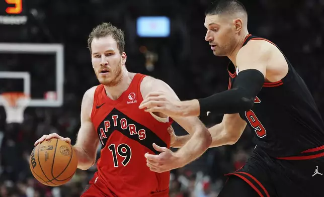 Toronto Raptors' Jakob Poeltl (19) drives past Chicago Bulls' Nikola Vucevic (9) during second-half NBA basketball game action in Toronto, Monday, Dec. 16, 2024. (Frank Gunn/The Canadian Press via AP)