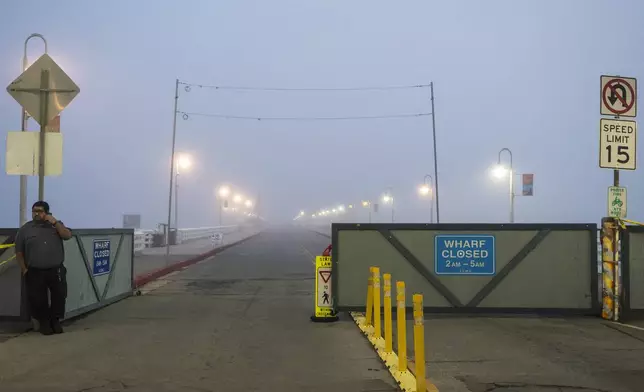 A security guard watches the entrance to the closed Santa Cruz Wharf in Santa Cruz, Calif., Monday, Dec. 23, 2024. (AP Photo/Nic Coury)