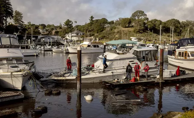 Recovery crews pump water from a semi-submerged boat in Santa Cruz Harbor after it was damaged during high surf in Santa Cruz, Calif., Tuesday, Dec. 24, 2024. (Santa Cruz/San Francisco Chronicle via AP)