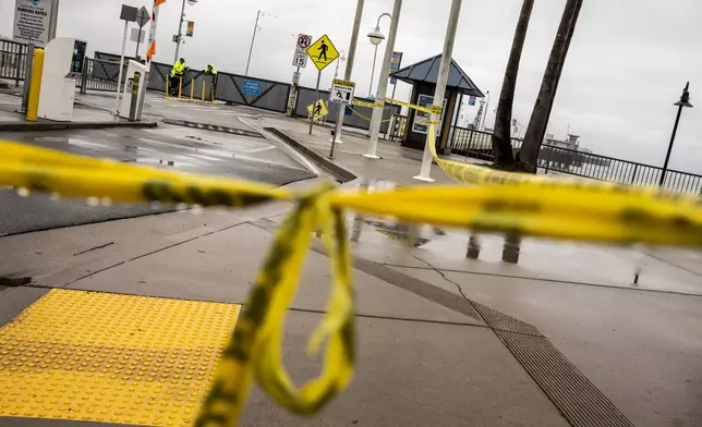 Caution tape hangs near the entrance of the closed Santa Cruz Wharf after a section of the wharf collapsed into the Pacific Ocean amidst heavy surf Monday in Santa Cruz, Calif., Tuesday, Dec. 24, 2024. (Stephen Lam/San Francisco Chronicle via AP)