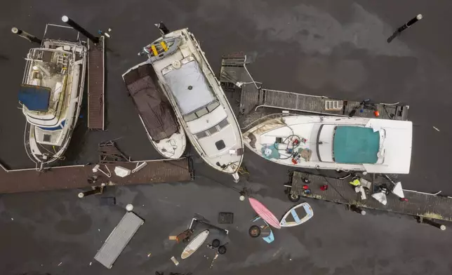 People pump water out of a boat in Santa Cruz Harbor in Santa Cruz, Calif., Tuesday, Dec. 24, 2024. (AP Photo/Nic Coury)