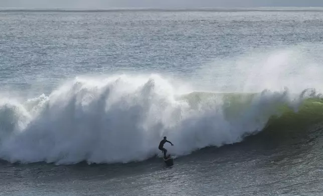 A surfer rides a large wave at Steamer Lane in Santa Cruz, Calif., Tuesday, Dec. 24, 2024. (AP Photo/Nic Coury)