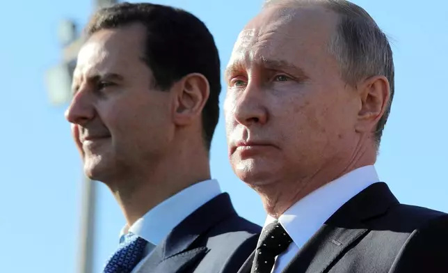 FILE - Russian President Vladimir Putin, right, and Syrian President Bashar Assad watch troops at the Hemeimeem air base in Syria, on Dec. 11, 2017. (Mikhail Klimentyev, Sputnik, Kremlin Pool Photo via AP, File)