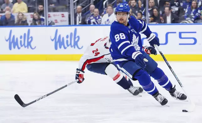 Toronto Maple Leafs right wing William Nylander (88) skates with the puck away from Washington Capitals center Connor McMichael (24) during first-period NHL hockey game action in Toronto, Friday, Dec. 6, 2024. (Cole Burston/The Canadian Press via AP)