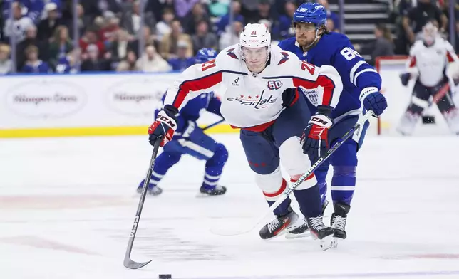 Washington Capitals center Aliaksei Protas (21) skates with the puck away from Toronto Maple Leafs right wing William Nylander (88) during third-period NHL hockey game action in Toronto, Friday, Dec. 6, 2024. (Cole Burston/The Canadian Press via AP)