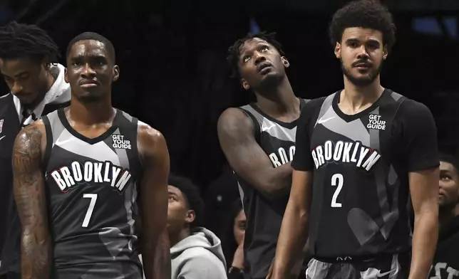 Brooklyn Nets' Shake Milton, left, Dorian Finney-Smith, center, and Cameron Johnson, right, watch an NBA basketball game from the bench during the second half against the Cleveland Cavaliers, Monday, Dec. 16, 2024, in New York. (AP Photo/Pamela Smith)