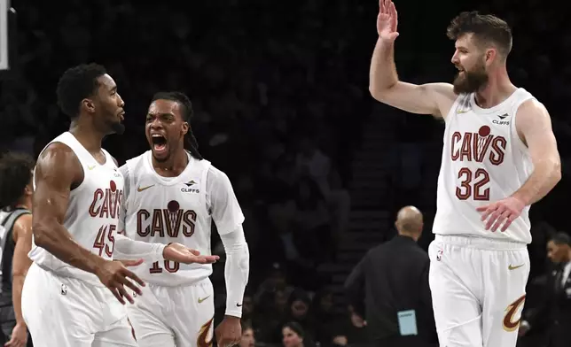 Cleveland Cavaliers' Donovan Mitchell, left, Darius Garland, center, and Dean Wade, right, react after Mitchell scored during the first half of an NBA basketball game against the Brooklyn Nets Monday, Dec. 16, 2024, in New York. (AP Photo/Pamela Smith)