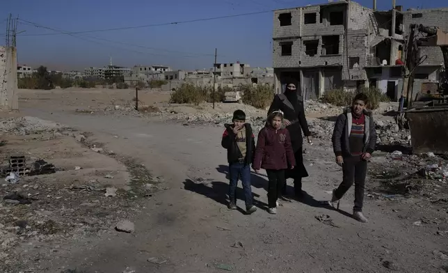 A Syrian family pass at an alley that was hit by the sarin struck during a 2013 chemical weapons attack that was blamed on then President Bashar Assad's forces, in Zamalka neighbourhood, on the outskirts of Damascus, Syria, Wednesday, Dec. 25, 2024. (AP Photo/Hussein Malla)