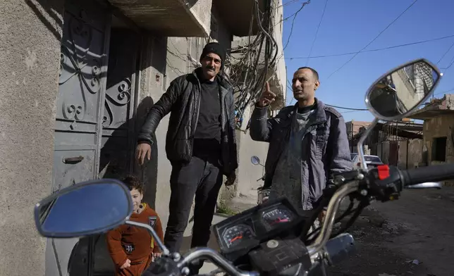 Hussein Arbeeni, 41, right, speaks with his brother Hassan Arbeeni, 42, right, outside their house at an alley that was hit by the sarin struck during a 2013 chemical weapons attack that was blamed on then President Bashar Assad's forces, in Zamalka neighbourhood, on the outskirts of Damascus, Syria, Wednesday, Dec. 25, 2024. (AP Photo/Hussein Malla)