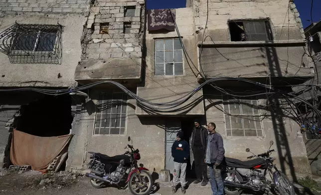 Hussein Arbeeni, 41, right, stands with his brother Hassan Arbeeni, 42, centre, outside their house at an alley that was hit by the sarin struck during a 2013 chemical weapons attack that was blamed on then President Bashar Assad's forces, in Zamalka neighbourhood, on the outskirts of Damascus, Syria, Wednesday, Dec. 25, 2024. (AP Photo/Hussein Malla)