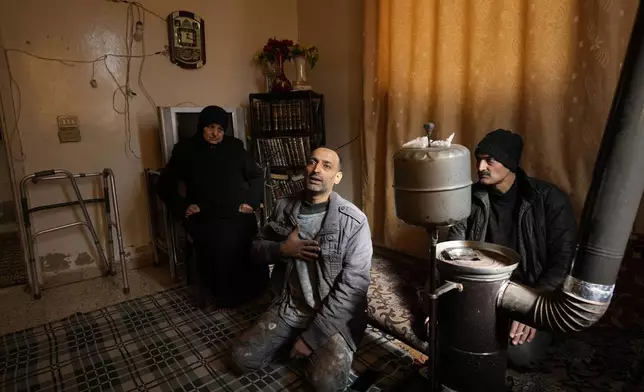 Hussein Arbeeni, 41, centre, sits between his mother mother Khadija Dabbas, 66, left, and his brother Hassan Arbeeni, 42, right, explains how he suffered from the sarin struck during a 2013 chemical weapons attack that was blamed on then President Bashar Assad's forces, in Zamalka neighbourhood, on the outskirts of Damascus, Syria, Wednesday, Dec. 25, 2024. (AP Photo/Hussein Malla)