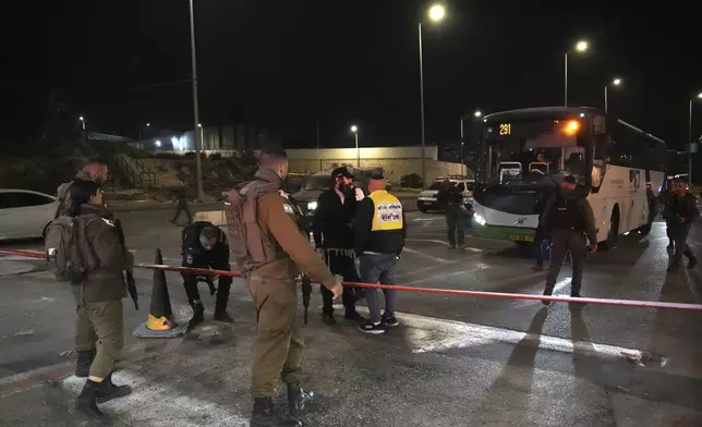 Israeli security forces work at the scene of a shooting attack on a bus near the West Bank town of Beit Jala, early Thursday, Dec. 12, 2024. (AP Photo/Mahmoud Illean)