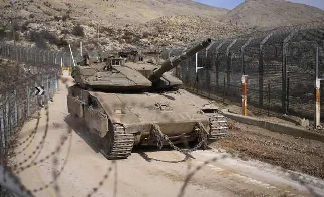 An Israeli tank maneuvers next to the security fence near the so-called Alpha Line that separates the Israeli-annexed Golan Heights from Syria, in the town of Majdal Shams, Wednesday, Dec. 11, 2024. (AP Photo/Matias Delacroix)