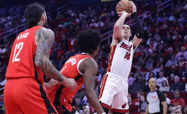 Miami Heat guard Tyler Herro (14) shoots a three-point shot as Houston Rockets center Steven Adams (12) and forward Amen Thompson, center, look on during the first half of an NBA basketball game Sunday, Dec. 29, 2024, in Houston. (AP Photo/Michael Wyke)