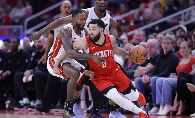 Houston Rockets guard Fred VanVleet (5) drives around Miami Heat forward Haywood Highsmith, left, as center Bam Adebayo, back, looks on during the first half of an NBA basketball game Sunday, Dec. 29, 2024, in Houston. (AP Photo/Michael Wyke)