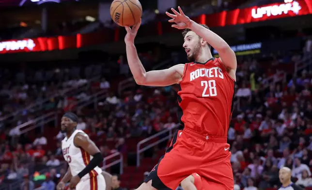 Houston Rockets center Alperen Sengun (28) dishes off a rebound as Miami Heat center Bam Adebayo, left, looks on during the first half of an NBA basketball game, Sunday, Dec. 29, 2024, in Houston. (AP Photo/Michael Wyke)