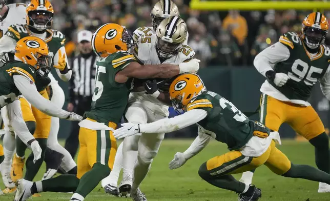 New Orleans Saints running back Kendre Miller (25) is stopped by Green Bay Packers linebacker Eric Wilson and safety Zayne Anderson, right, during the first half of an NFL football game, Monday, Dec. 23, 2024, in Green Bay, Wis. (AP Photo/Morry Gash)