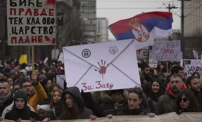 People stopping traffic, stand in silence during ongoing protests that erupted after a concrete canopy fell last month and killed 15 people in front of the government building in Belgrade, Serbia, Wednesday, Dec. 25, 2024. (AP Photo/Darko Vojinovic)