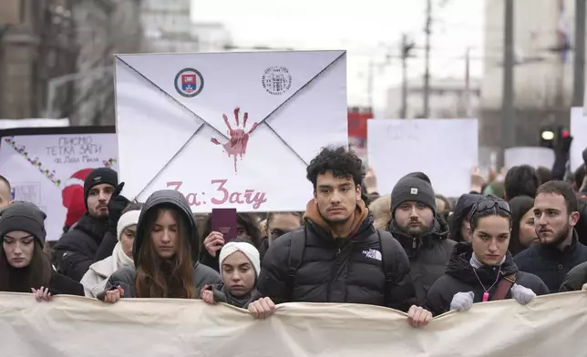 People stopping traffic, stand in silence during ongoing protests that erupted after a concrete canopy fell last month and killed 15 people in front of the government building in Belgrade, Serbia, Wednesday, Dec. 25, 2024. (AP Photo/Darko Vojinovic)